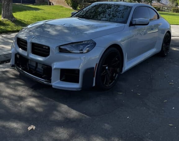 Silver BMW M2 with black wheels parked on a sunny street