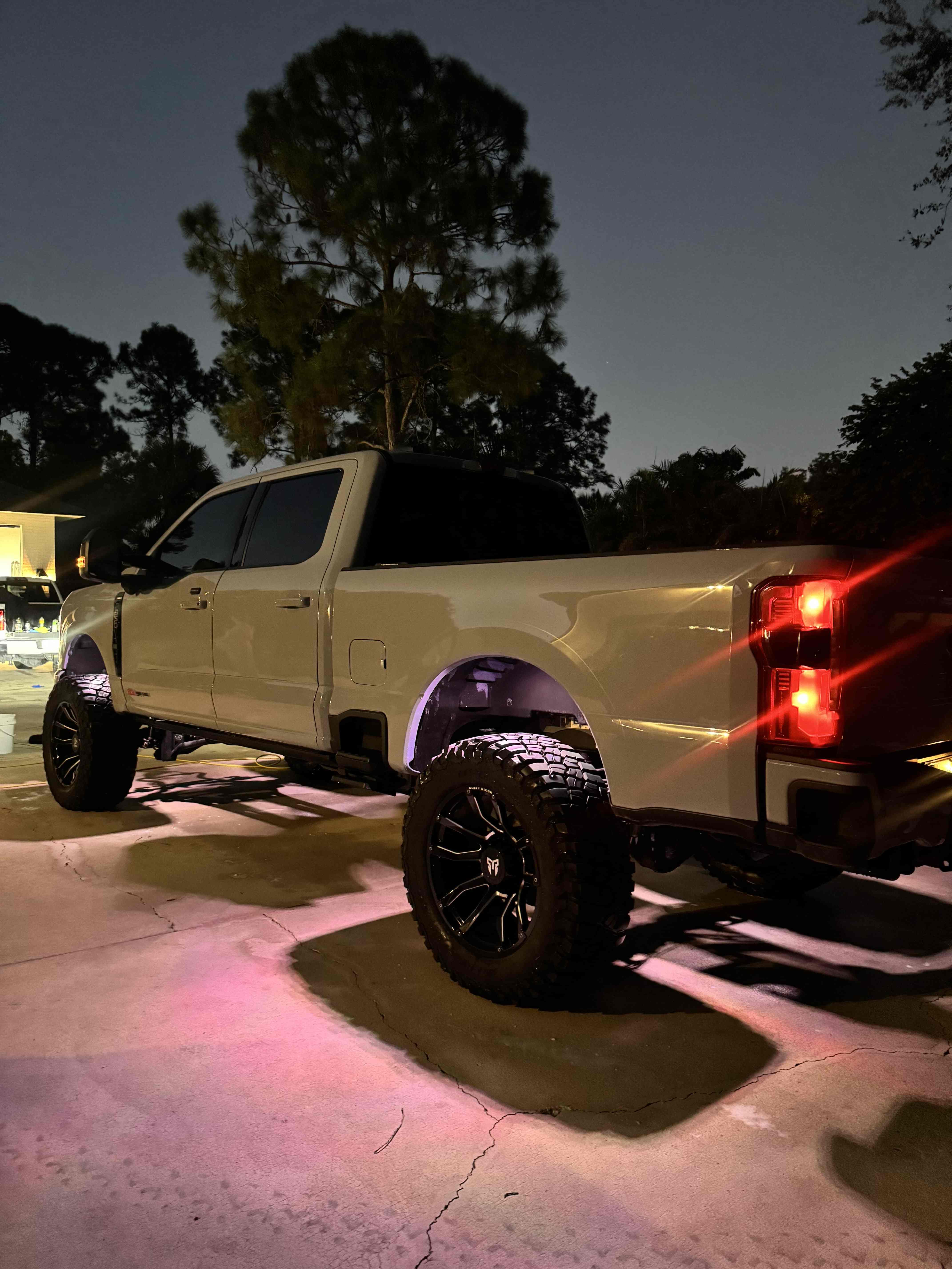 Lifted Ford Super Duty truck glowing under lights at night after a detail